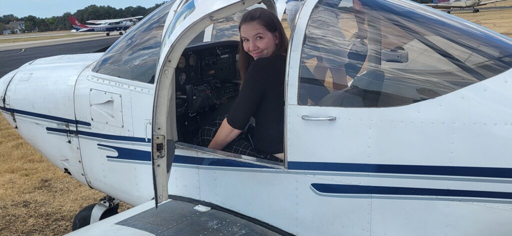 Racheal sitting in the pilot seat of a 1970's tomahawk plane
